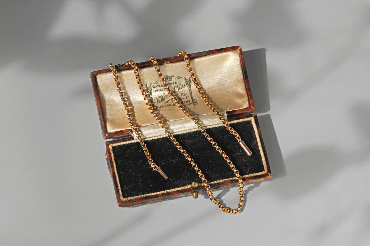 Antique belcher link chain in 9ct gold, displayed on an antique jewellery box in the sun 
