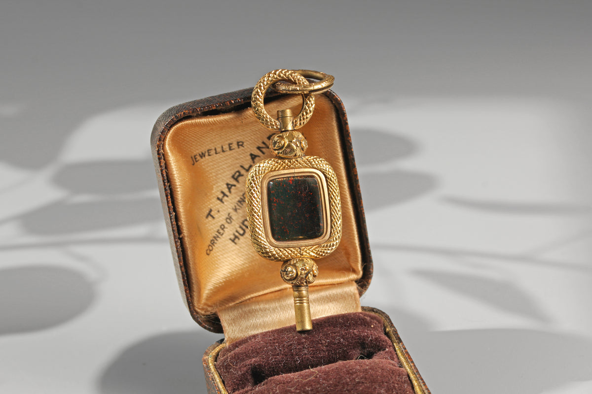 Antique bloodstone watch key in warm gold tones photographed in antique jewellery box
