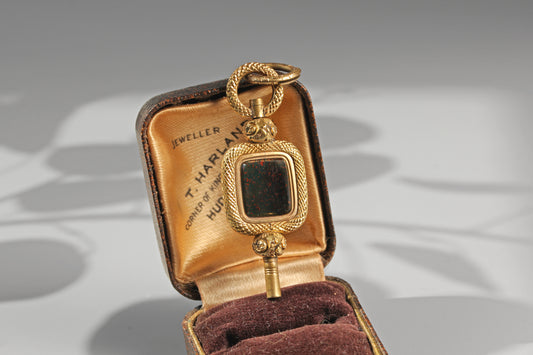 Antique bloodstone watch key in warm gold tones photographed in antique jewellery box
