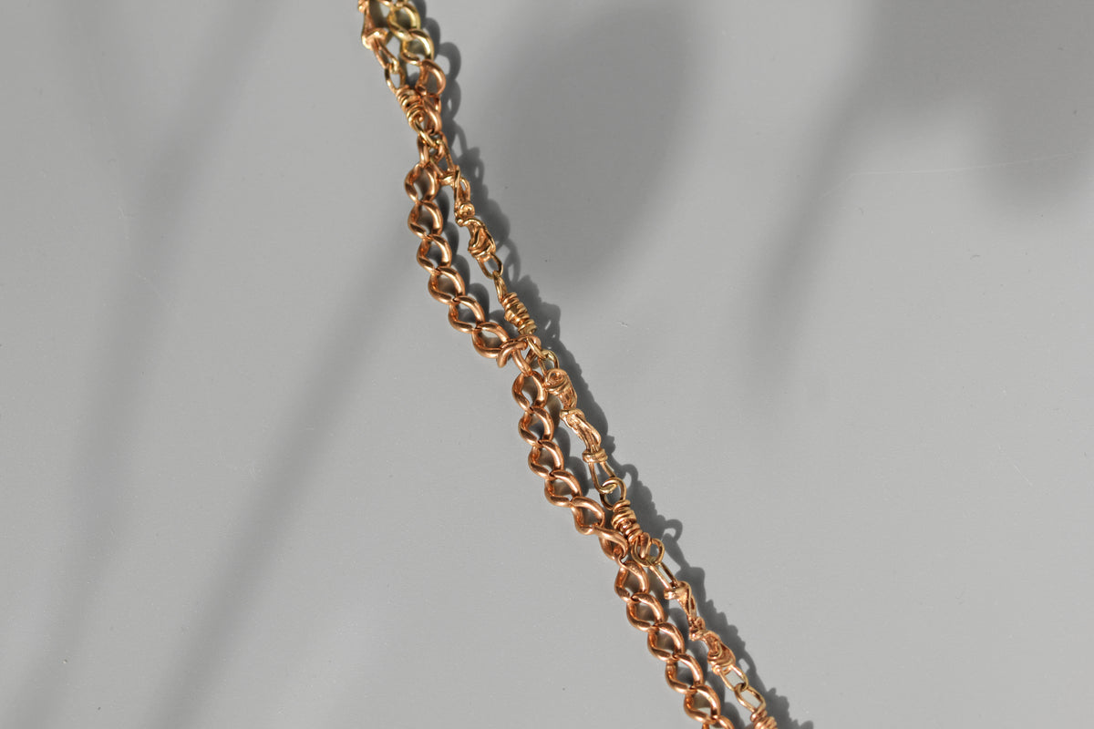 Close up of curb link and fancy link double strand Albert chain bracelet, in 9ct gold 