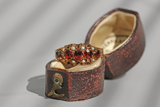 Antique 9ct gold garnet and pearl ring displayed in antique ring box
