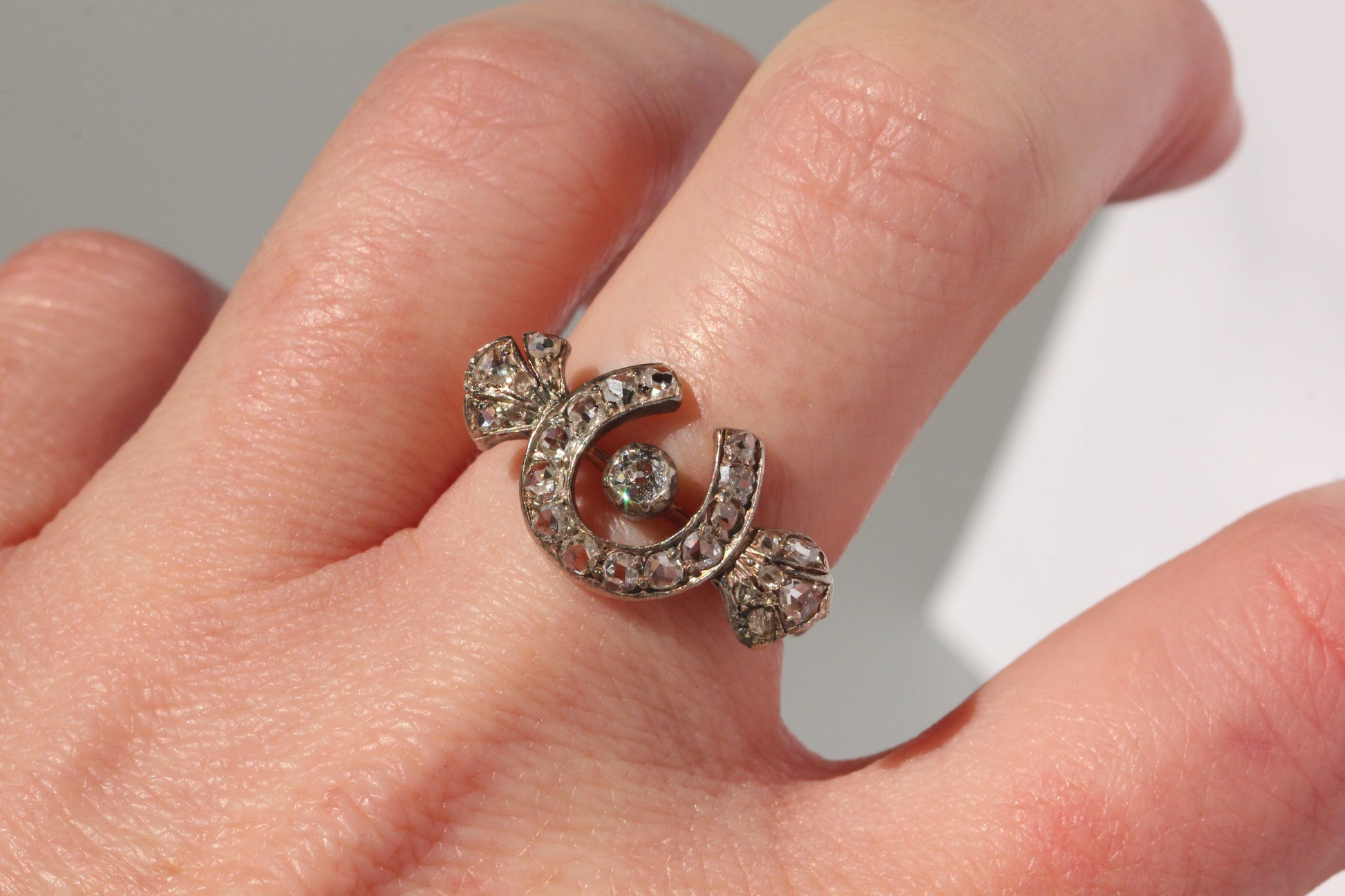 Antique diamond horseshoe ring worn on hand
