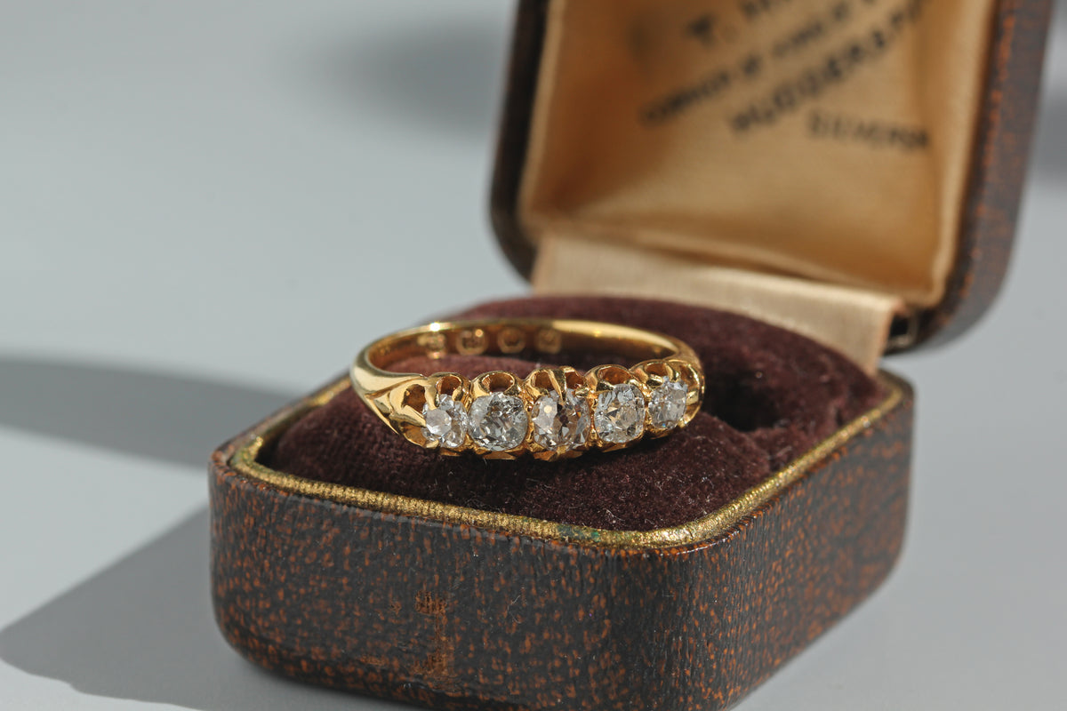 An antique edwardian five stone old mine cut diamond ring in 18ct gold, displayed in antique jewellery box