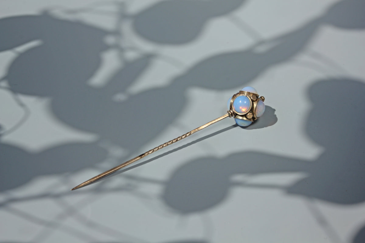 Antique opaline glass orb pin with decorative gold studs, crafted in 9ct gold with a twisted stem displayed on a neutral grey background