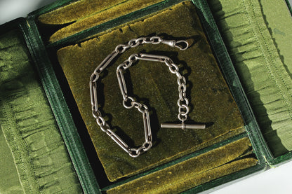 Antique 925 sterling silver trombone or paperclip link Albert watch chain with dog clip and t bar, displayed on antique jewellery box