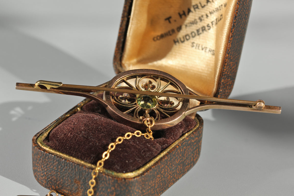 A rear view of an edwardian 9ct gold brooch with the clasp and pin details, photographed on antique ring box