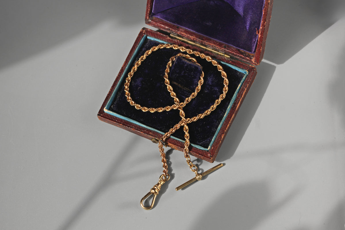 Antique solid 9ct gold Albert chain with t-bar and dog clip, with a decorative fancy rope link displayed on an antique jewellery box