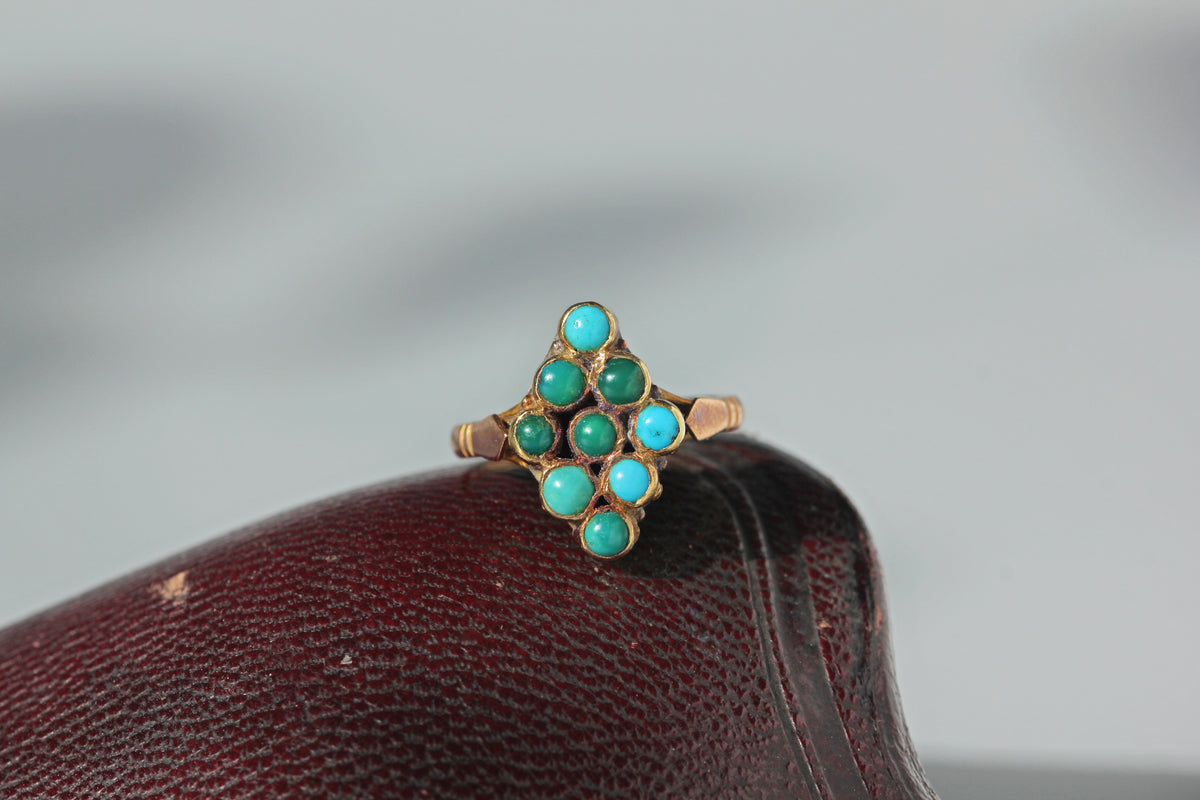An antique 9ct gold turquoise ring with a navette or lozenge shaped gallery, displayed on a leather antique jewellery box