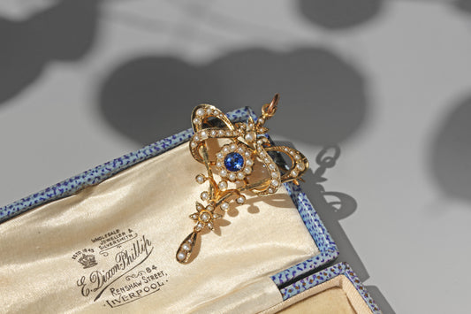 Antique blue paste and seed pearl lavaliere pendant in 9 carat gold resting on an antique jewellery box