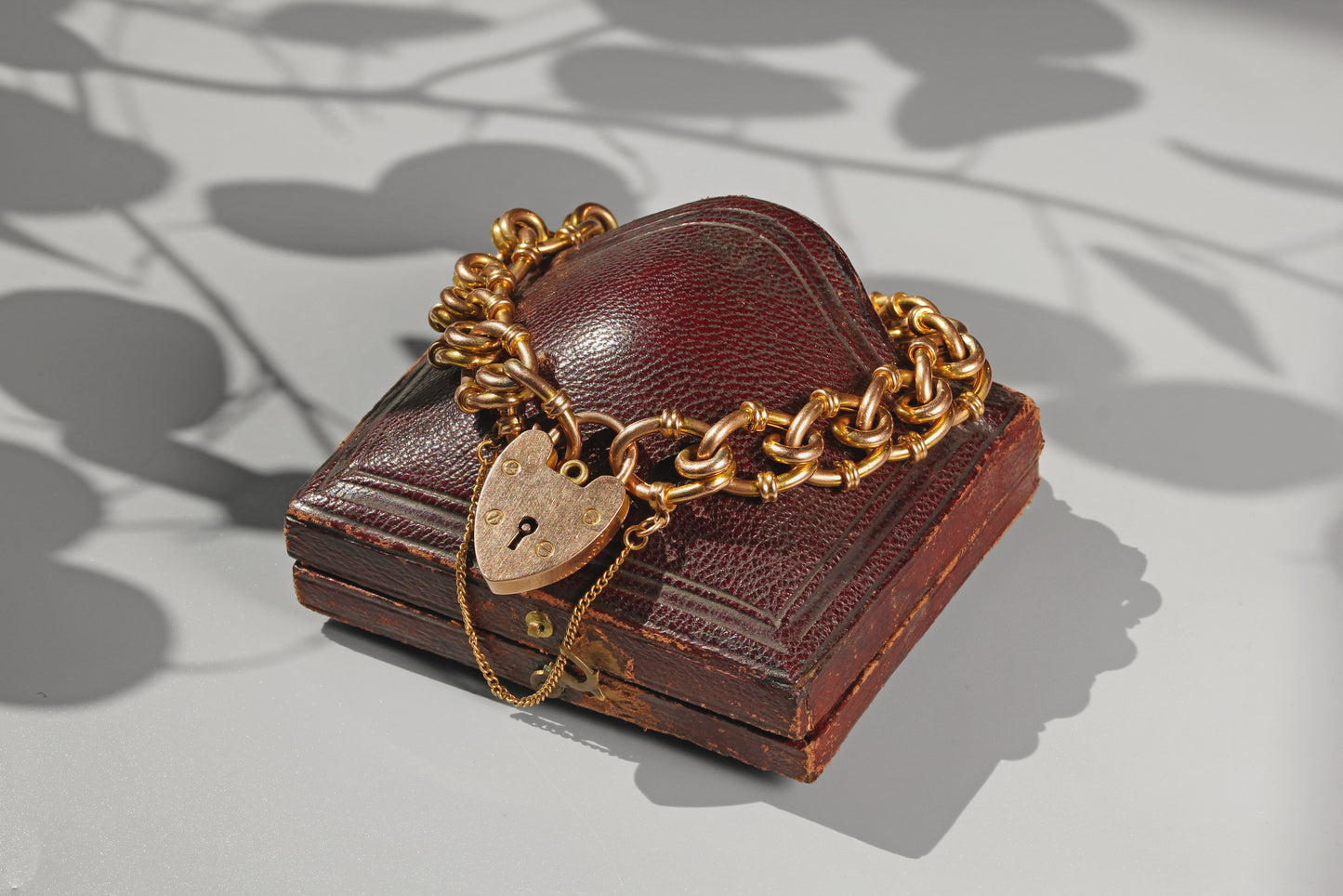 Antique fancy link heart padlock bracelet in 9 carat gold displayed on a leather jewellery box

