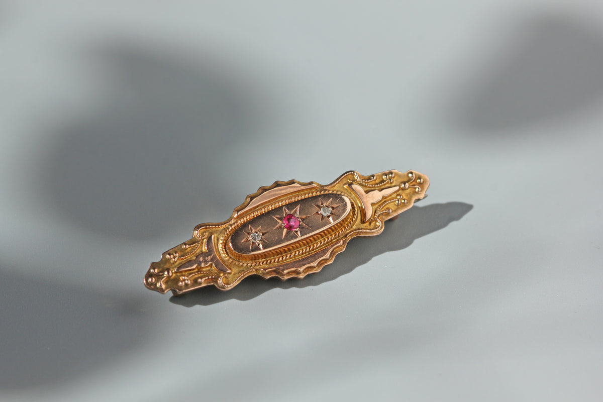 Celestial trilogy brooch with diamonds and pink spinel, crafted in 9ct gold with star shaped celestial settings on a neutral grey background