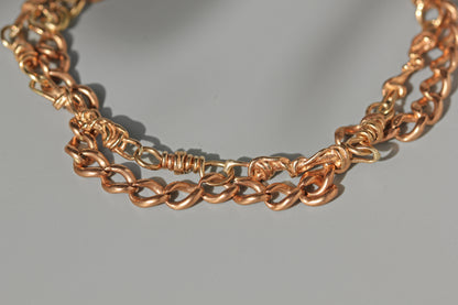 A close-up of 9ct chain bracelet with twisted and knotted link details, resting on a neutral gray background.
