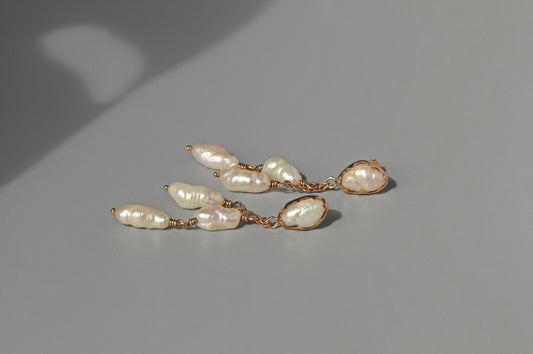 Pearl earring with gold setting on a gray background