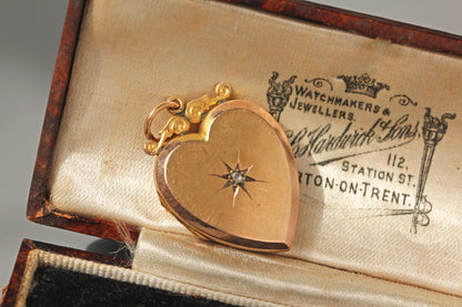 A heart shaped vintage 1960s locket, crafted in 9ct gold with a rose cut diamond and  celestial star shaped setting holding a diamond, displayed in an antique jewellery box