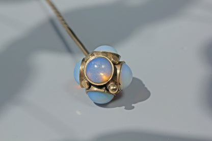 An antique stick pin with orbs of moonlike opaline cabochons, crafted in 9ct gold