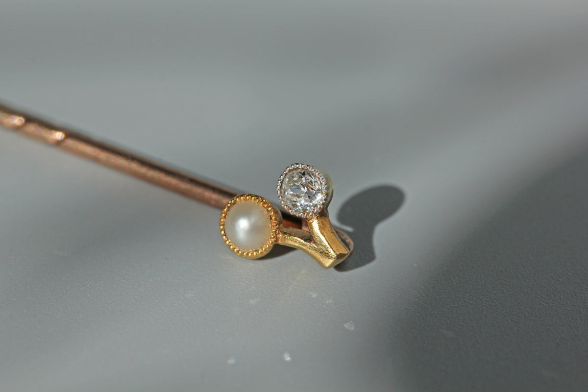 Close up of antique old cut diamond on a 18ct gold stick pin with a pearl