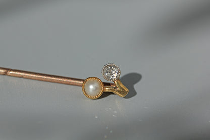 Close up of pearl and old cut diamond stick pin with a cherry shaped mount, crafted in buttery 18ct gold and dating to the art deco era