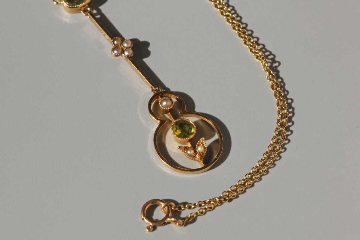 Close up of openwork antique 15ct gold pendant, with peridot and pearl accents