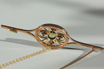 Detailed view of the back of an antique gold brooch with a peridot stone at the centre and the antique clasp details shown