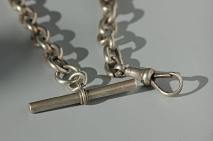 A close up of sterling silver antique Albert chain components, a t-bar and a dog clip or lobster clasp