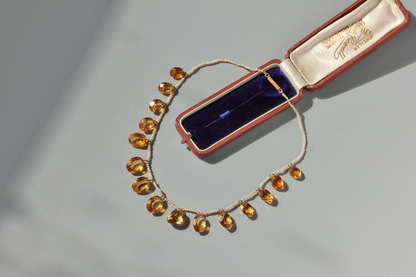 Late Victorian Edwardian citrine pearl necklace with 15ct gold clasp displayed beside antique jewellery box