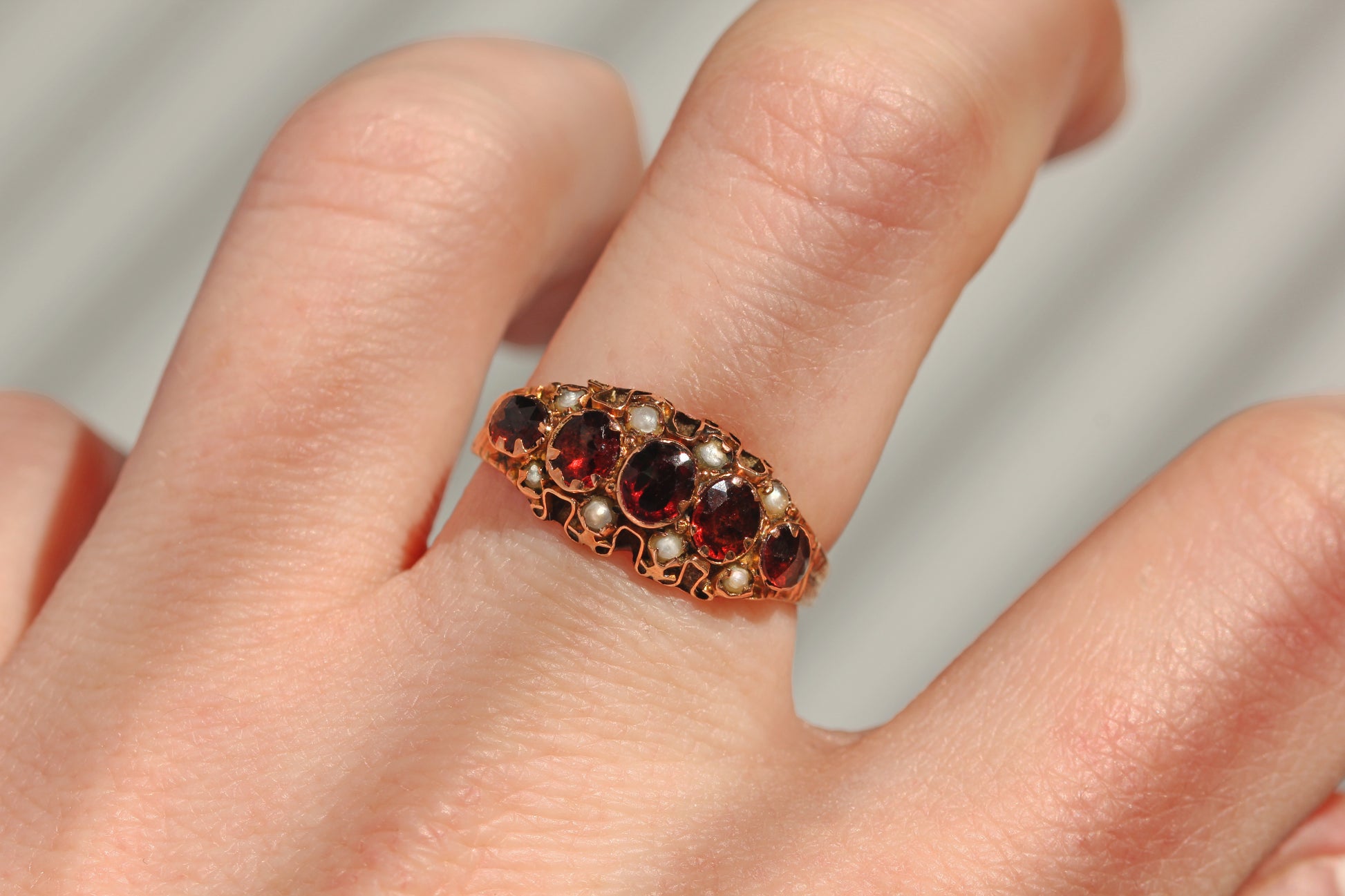 Antique garnet and pearl five stone ring in 9 carat gold worn on hand

