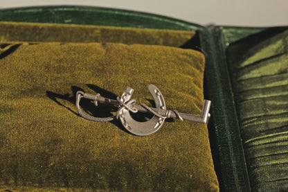 Antique sterling silver riding crop and horseshoe brooch with dramatic shadowing