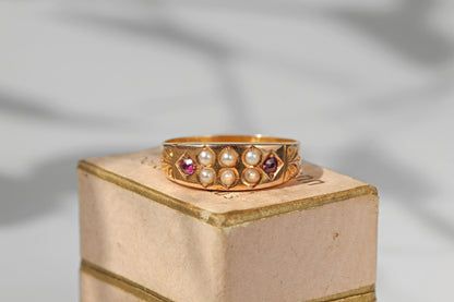Antique victorian 15ct gold band ring decorated with rubies and pearls, displayed on vintage jewellery box