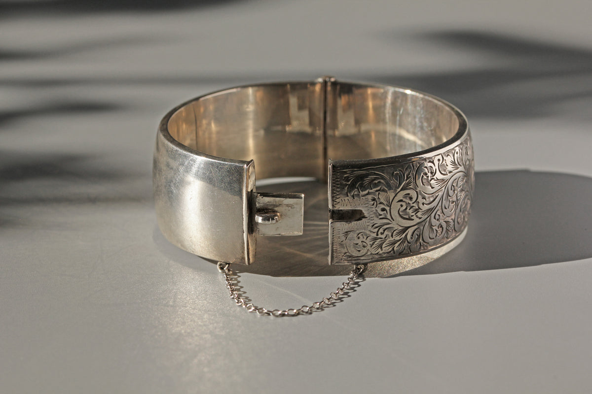 Silver bracelet with intricate design on a reflective surface, close up of the last