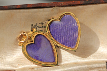 A blue silk lined vintage heart shaped double photo locket in 9ct gold, displayed in an antique jewellery