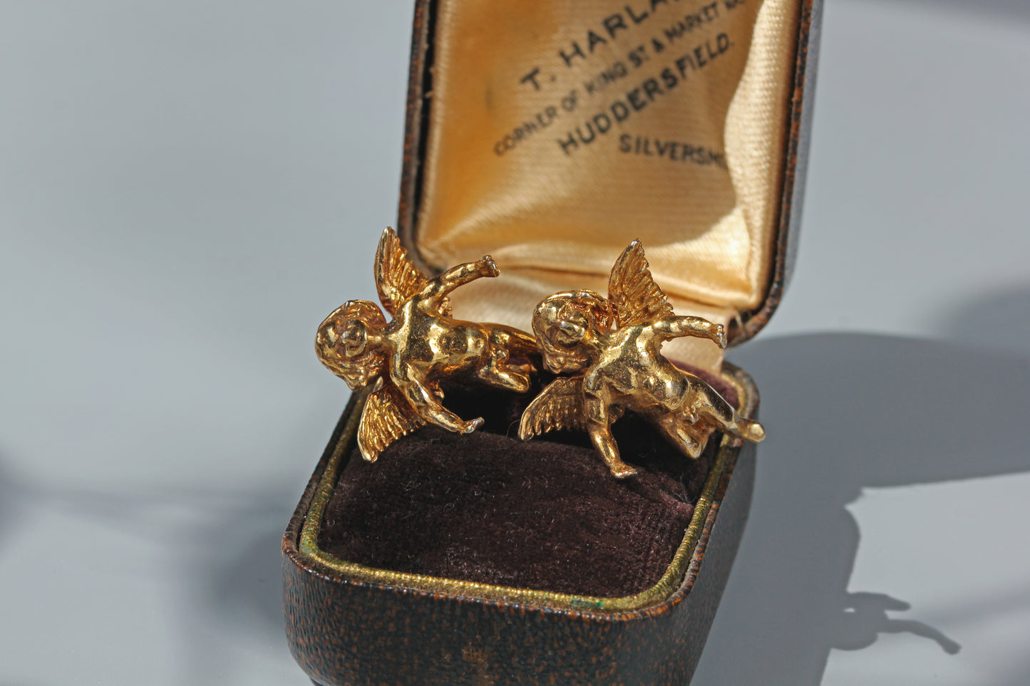 Close up of vintage angel earrings showing textured wings and sculptural detailing