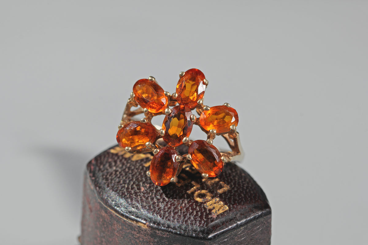 Vintage orange topaz statement ring with bright oval cut stones arranged as a flower cluster
