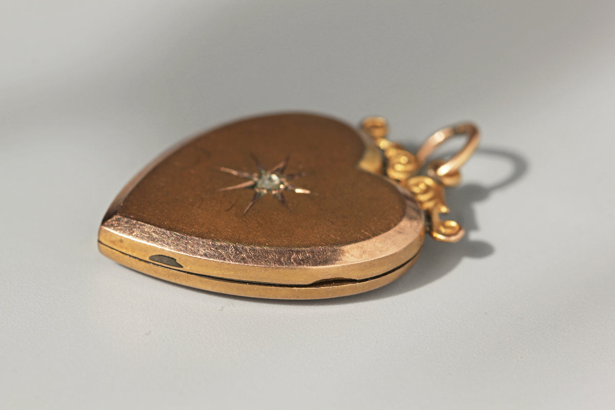 A close up of the opening of a 9ct gold vintage locket pendant, on gray background